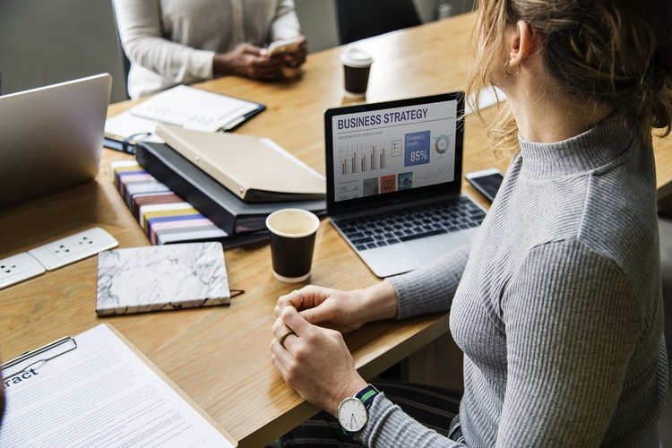 Woman sitting at table with computer, binders and pads