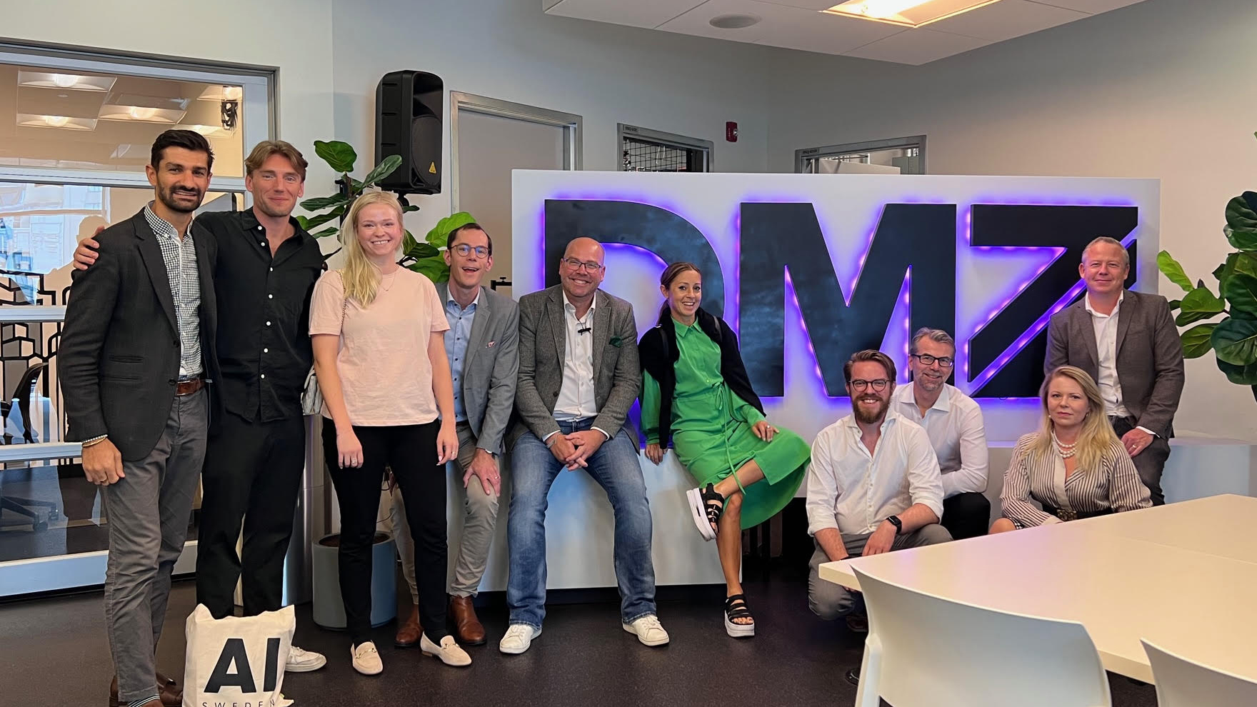 Swedish delegation of 10 people smiling at the camera in front of the DMZ sign